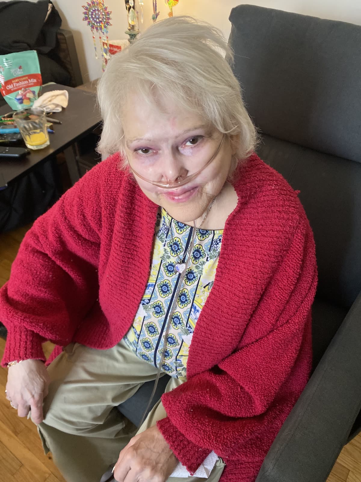 A resident in a red cardigan sitting in her armchair by the window