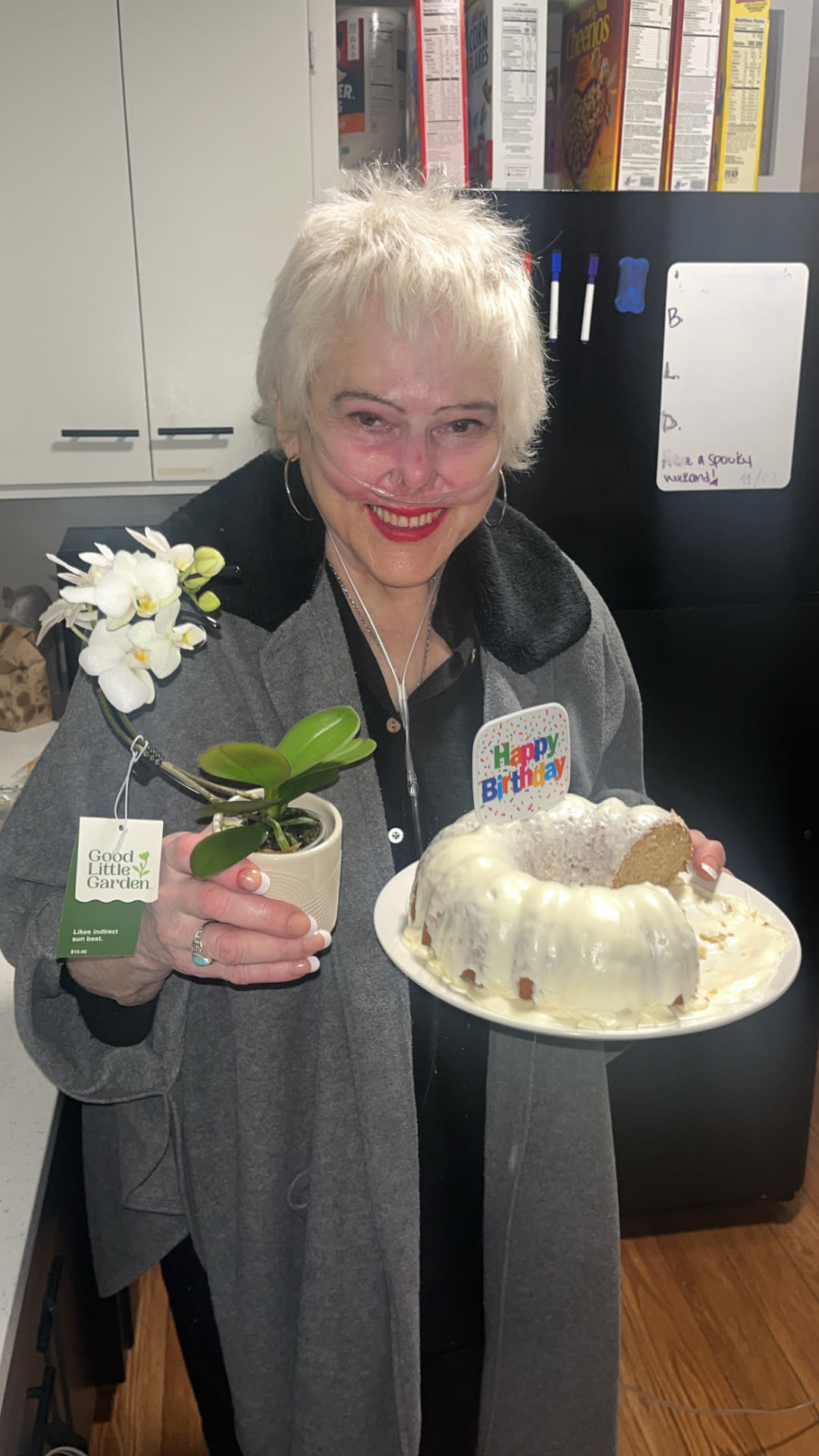A resident holding a birthday bundt cake and a small orchid in the kitchen